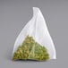 A white mesh bag with pyramid sachets of green tea.