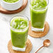 A spoon stirring two glasses of green Jade Leaf Ceremonial Matcha.