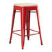 A red Lancaster Table & Seating outdoor backless counter height stool with a tan cushion.