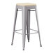 A grey Lancaster Table & Seating outdoor backless barstool with a tan cushion.