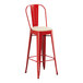 A Lancaster Table & Seating red metal outdoor barstool with a tan cushion.