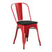 A red metal Lancaster Table & Seating outdoor restaurant chair with a black cushion.