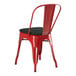 A red metal Lancaster Table & Seating outdoor cafe chair with black cushion.