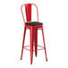 A red Lancaster Table & Seating outdoor cafe barstool with black cushion.