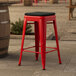 A red Lancaster Table & Seating backless outdoor counter height stool with a black cushion.