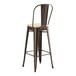 A brown metal Lancaster Table & Seating outdoor restaurant bar stool with a tan cushion.