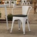 A Lancaster Table & Seating white outdoor arm chair with a black cushion.