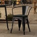 A Lancaster Table & Seating black outdoor arm chair with a black cushion on a patio table.