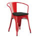 A red metal Lancaster Table & Seating outdoor arm chair with a black cushion.