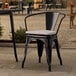 A Lancaster Table & Seating black outdoor arm chair with a gray cushion on a patio.