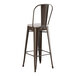 A brown metal Lancaster Table & Seating outdoor restaurant bar stool with a gray cushion.
