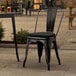 A Lancaster Table & Seating black metal outdoor cafe chair with black cushion.