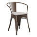 A brown metal Lancaster Table & Seating outdoor arm chair with a gray cushion.