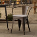 A Lancaster Table & Seating outdoor arm chair with a gray cushion on a patio table.