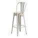 A Lancaster Table & Seating metal barstool with a tan cushion.