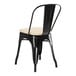 A Lancaster Table & Seating black metal outdoor cafe chair with tan cushion.