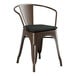 A brown metal Lancaster Table & Seating outdoor arm chair with a black cushion.