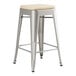 A Lancaster Table & Seating metal backless counter height stool with a tan cushion.
