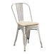 A Lancaster Table & Seating metal cafe chair with a tan cushion.