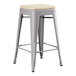 A Lancaster Table & Seating gray metal outdoor backless counter height stool with a tan cushion.