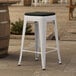 A Lancaster Table & Seating white outdoor backless counter height stool with a black cushion.