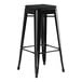 A Lancaster Table & Seating black metal outdoor backless bar stool with a black cushion.