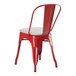A Lancaster Table & Seating red metal outdoor cafe chair with a white cushion.