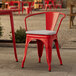 A red Lancaster Table & Seating outdoor arm chair with a gray cushion on a patio.