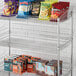 A Regency chrome metal display basket filled with bags of snacks.