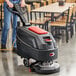 A person using a Viper walk behind floor scrubber with wheels to clean a floor.