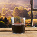 An Anchor Hocking Savore rim tempered tumbler filled with brown liquid on a wooden table.