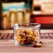 An Anchor Hocking rim tempered tumbler filled with mixed nuts on a table in a cocktail bar.