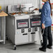 A woman standing next to a Henny Penny liquid propane gas fryer on a counter.