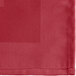 A red cloth napkin with a square design on the edge.