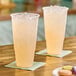 Two Choice clear plastic cups of liquid with ice on napkins.