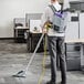 A man wearing a ProTeam GoFit backpack vacuum cleaner in a corporate office cafeteria.