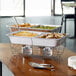 A hotel buffet table with Choice disposable wire chafer stands holding trays of food.