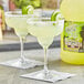 Two glasses of Finest Call margaritas with lime slices on a table.