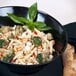 A black slanted melamine bowl filled with pasta, broccoli, and cheese.