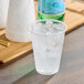 A clear plastic Choice cup filled with ice on a table.