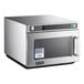 An Amana stainless steel commercial microwave on a counter with a flag sticker.