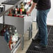 A man pouring a drink into a Regency underbar ice bin with a cold plate.