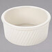 A white Tuxton Eggshell Swirl ramekin with a wavy design on a gray surface.