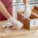 A person wearing gloves using Western Plastics perforated film to wrap a box.