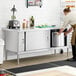 A woman preparing food on a Steelton stainless steel enclosed base table in a professional kitchen.