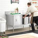 A person in an apron opening a Steelton stainless steel table with sliding doors.