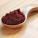 A spoon filled with blackberry powder.