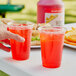 A hand holding a plastic cup with Sqwincher Fruit Punch.