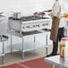 A man in a chef's uniform cooking food on a Cooking Performance Group countertop range.