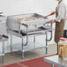 A man in an apron using a Cooking Performance Group thermostatic griddle on a stainless steel counter.
